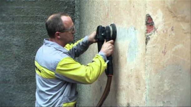 Процесс снятия старой краски со стены с использованием болгарки
